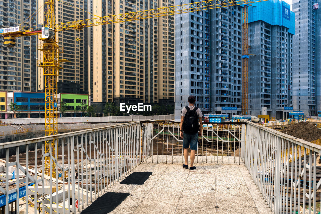 Woman walking on bridge against buildings in city