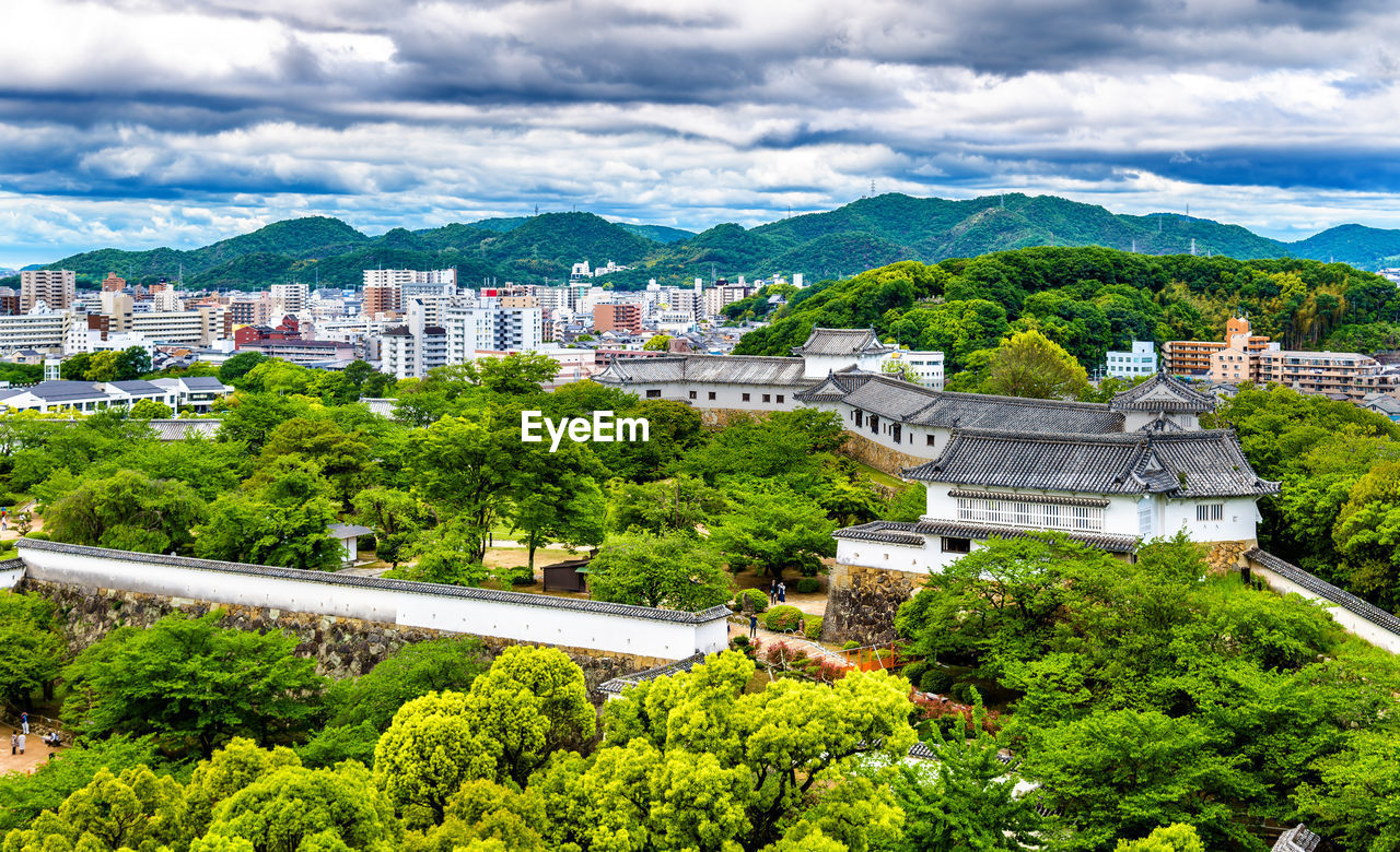 HIGH ANGLE VIEW OF TREES AND BUILDINGS IN CITY AGAINST SKY