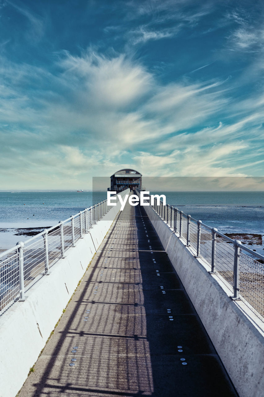 View of boardwalk leading towards sea against sky