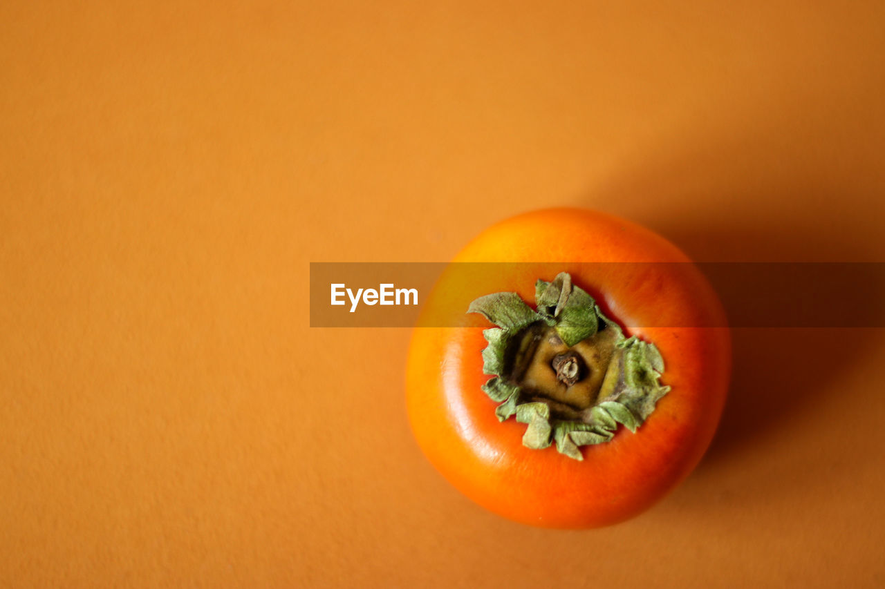 Close-up of persimmon against orange background