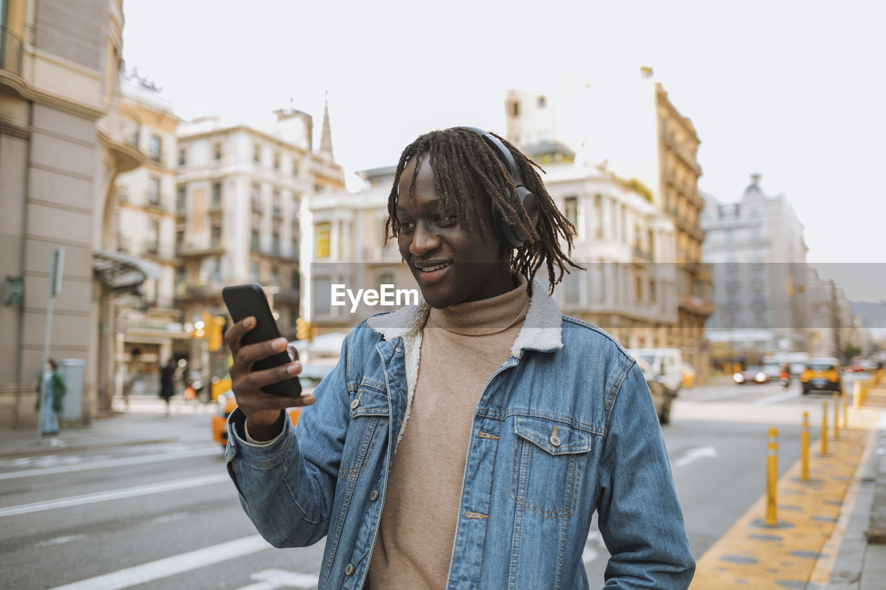 Smiling man using phone in city