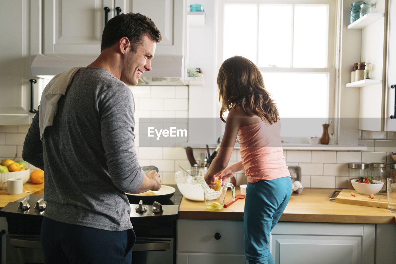Happy father and daughter preparing food in kitchen at home