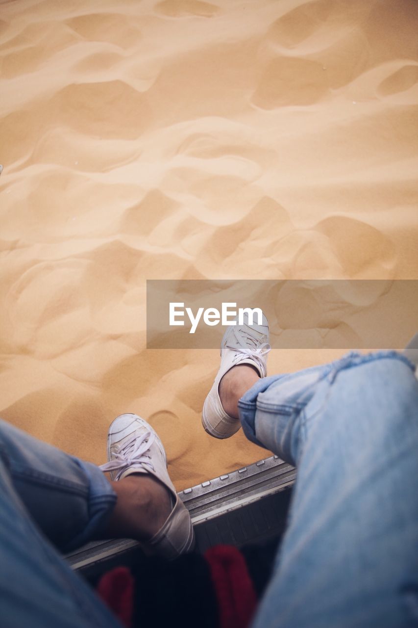 Low section of man on sand in desert