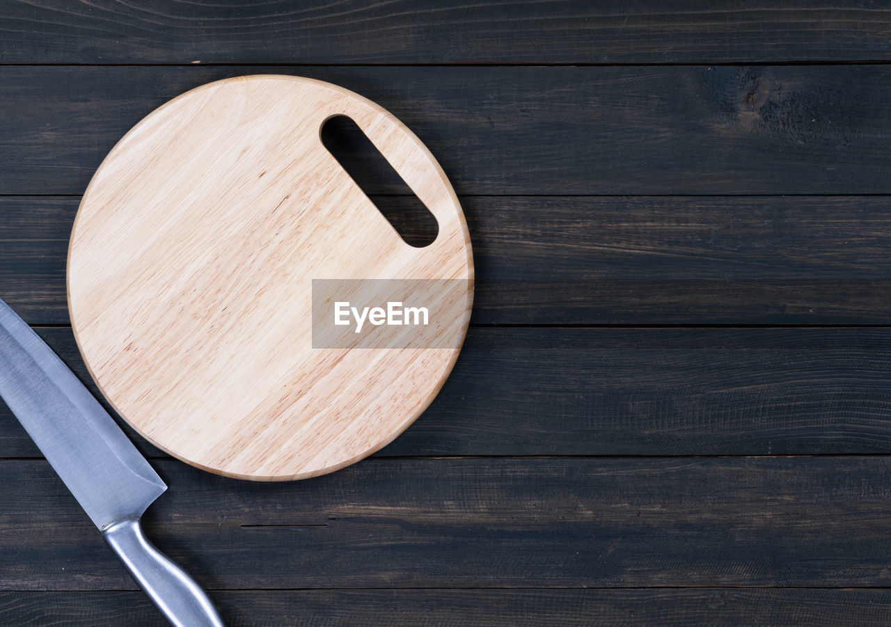 Close up kitchen knife and wooden round empty cutting board on a wooden table