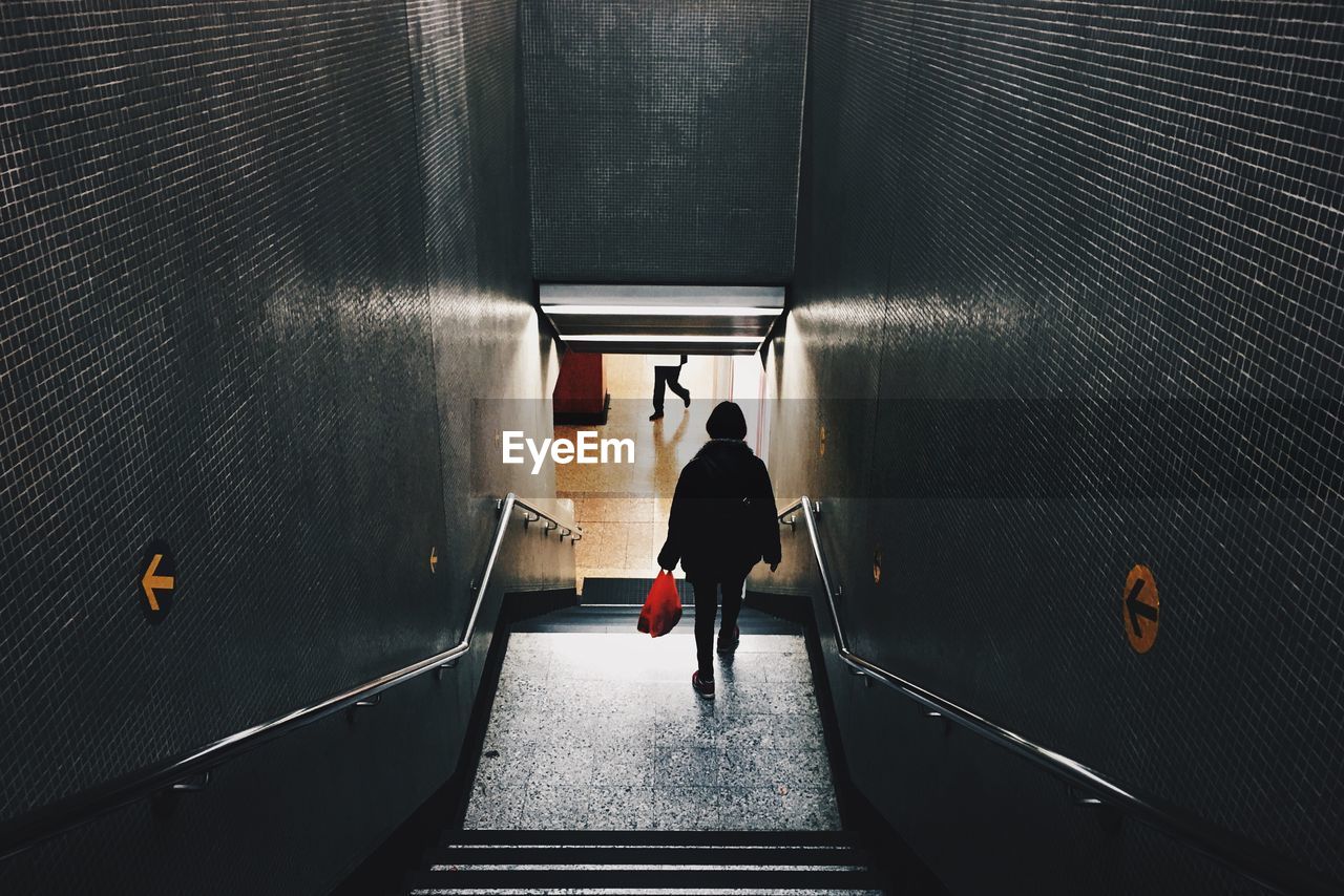 Rear view of woman walking on staircase in building