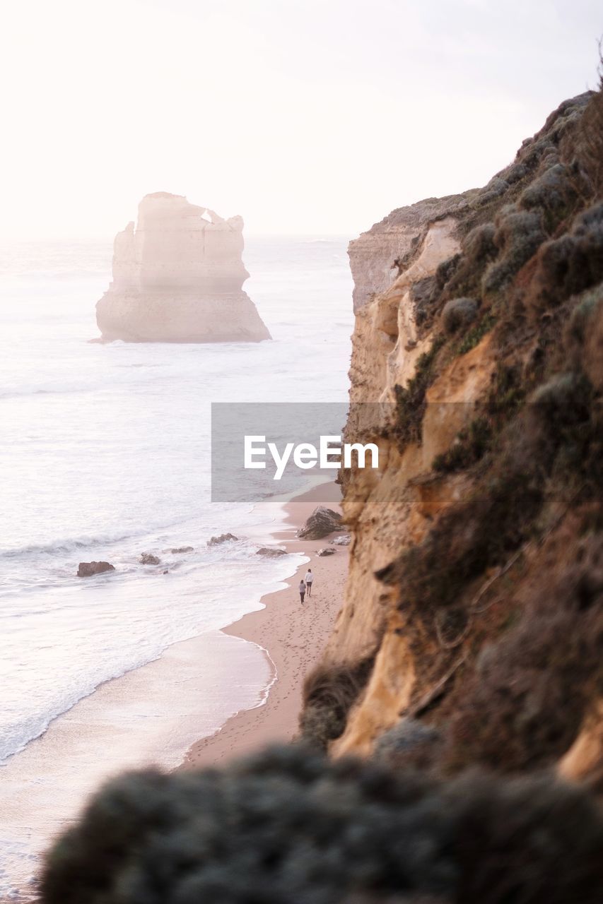 Rock formations at beach against clear sky