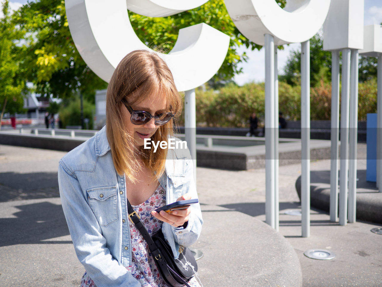 Portrait of young woman using mobile phone while standing in city