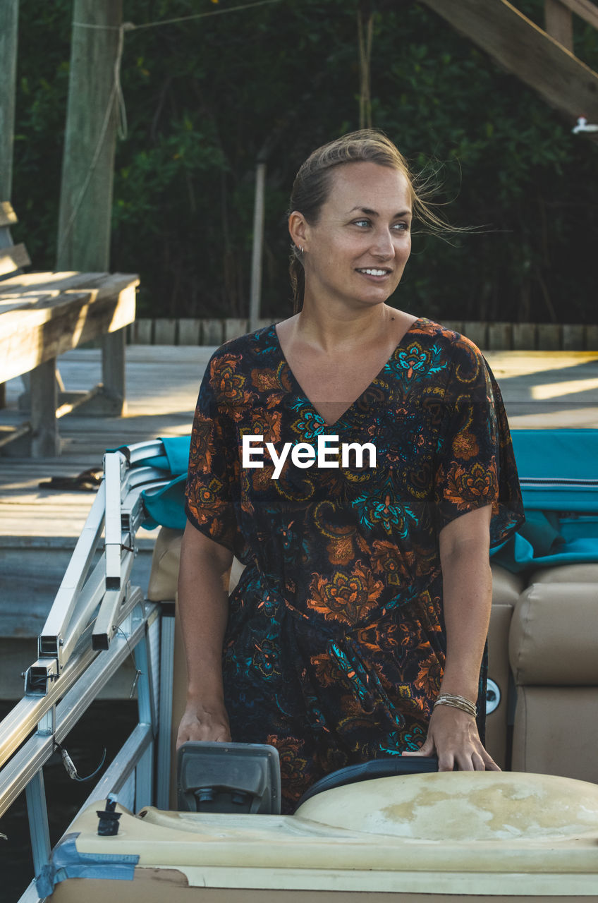 Smiling woman looking away while standing in boat