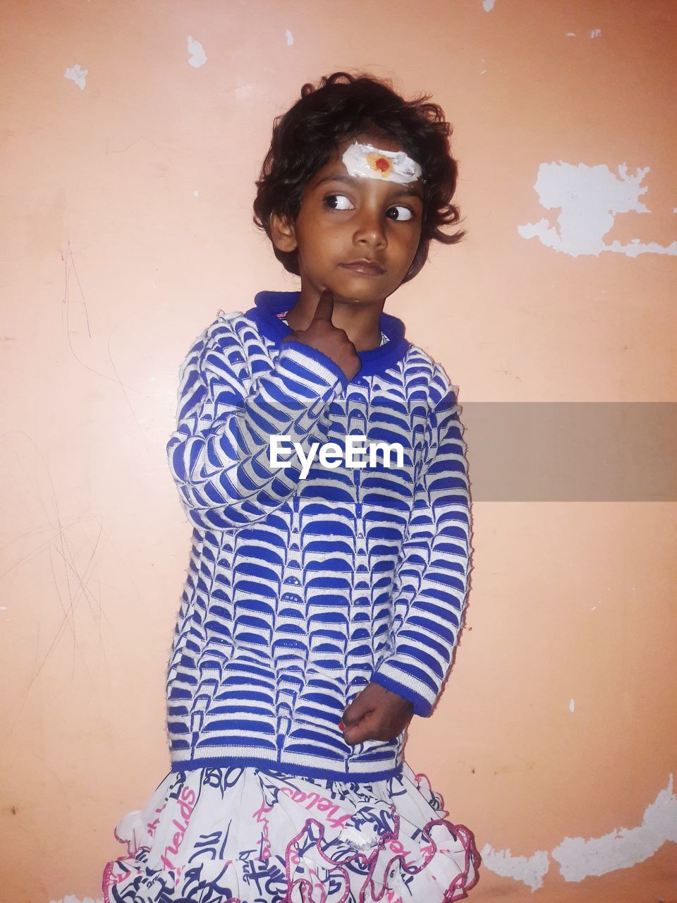 Girl looking away while standing against wall