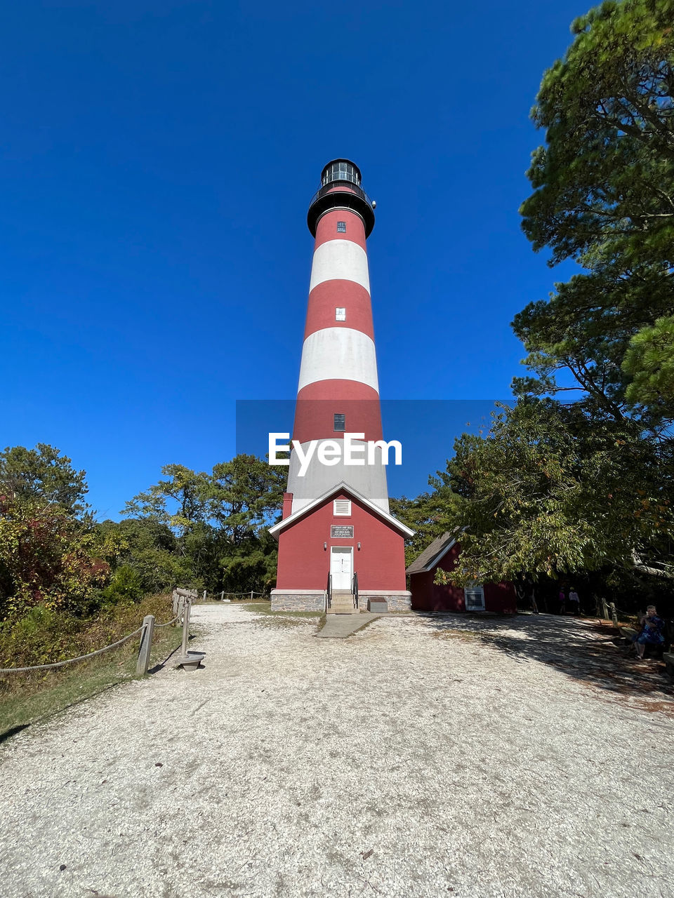 lighthouse, guidance, architecture, built structure, blue, tower, sky, building exterior, nature, security, protection, plant, building, clear sky, tree, no people, day, striped, outdoors, communication, sunny, land, red, house, travel destinations, sign, water, beach, sunlight, landscape, observation tower