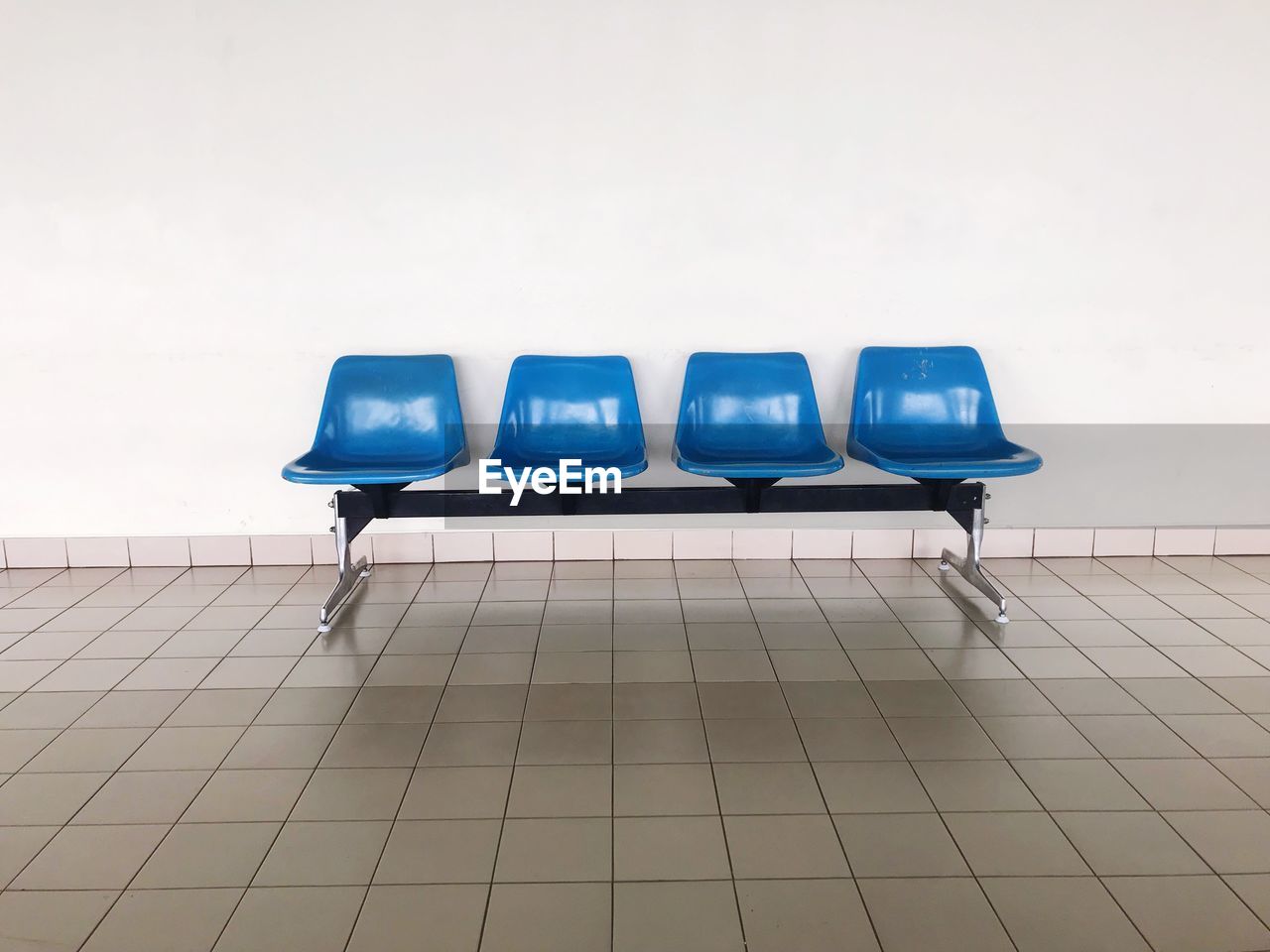 Empty chairs against tiled wall