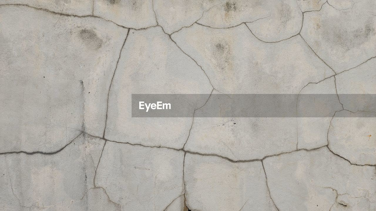 backgrounds, cracked, full frame, textured, pattern, no people, floor, wall, flooring, dry, architecture, close-up, built structure, arid climate, climate, nature, wall - building feature, rough, drought, road surface, stone wall, day, outdoors, gray, land, environment, stone material, dirt, barren, weathered, scenics - nature