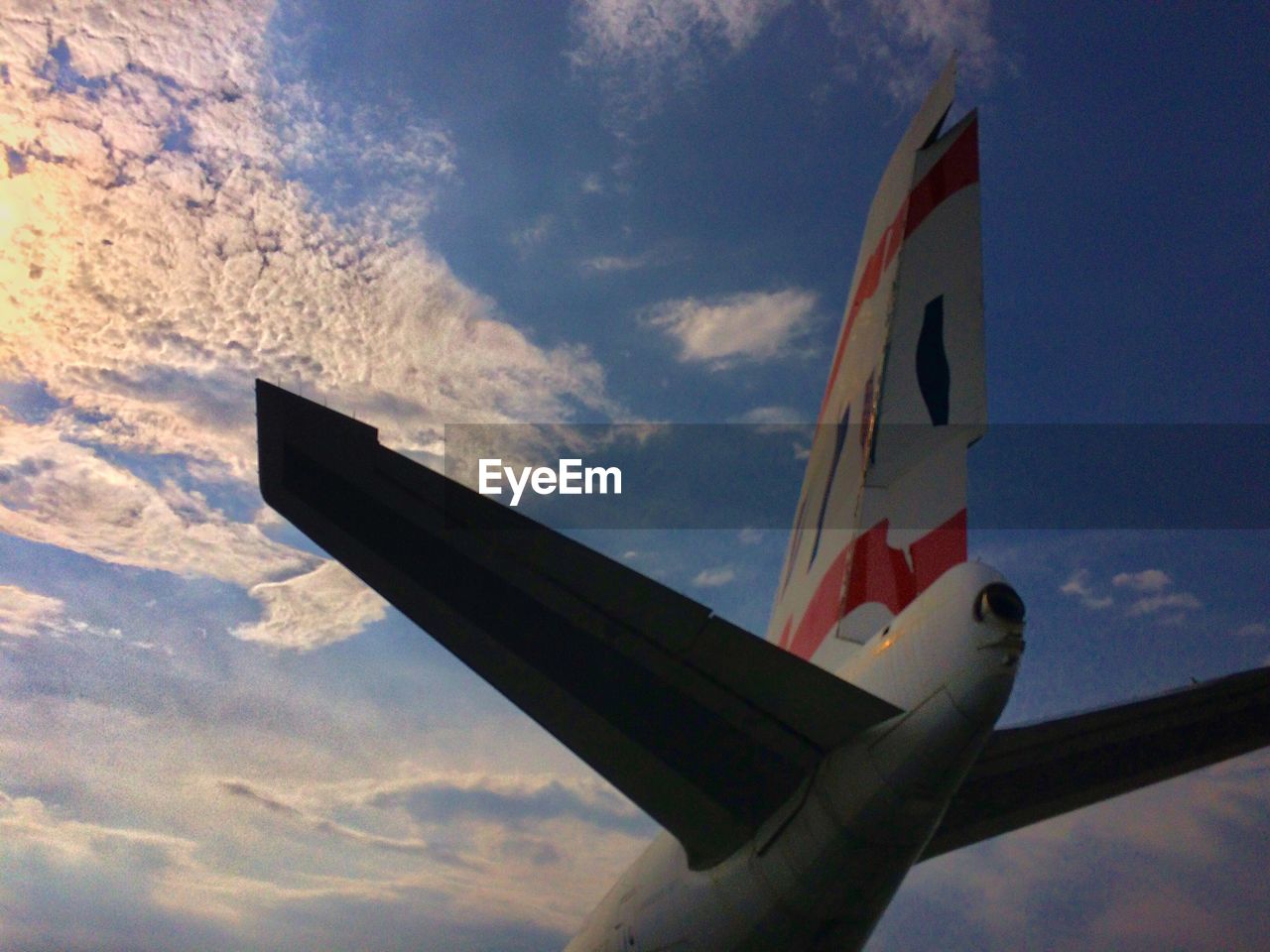 LOW ANGLE VIEW OF AIRPLANE FLYING AGAINST CLOUDY SKY