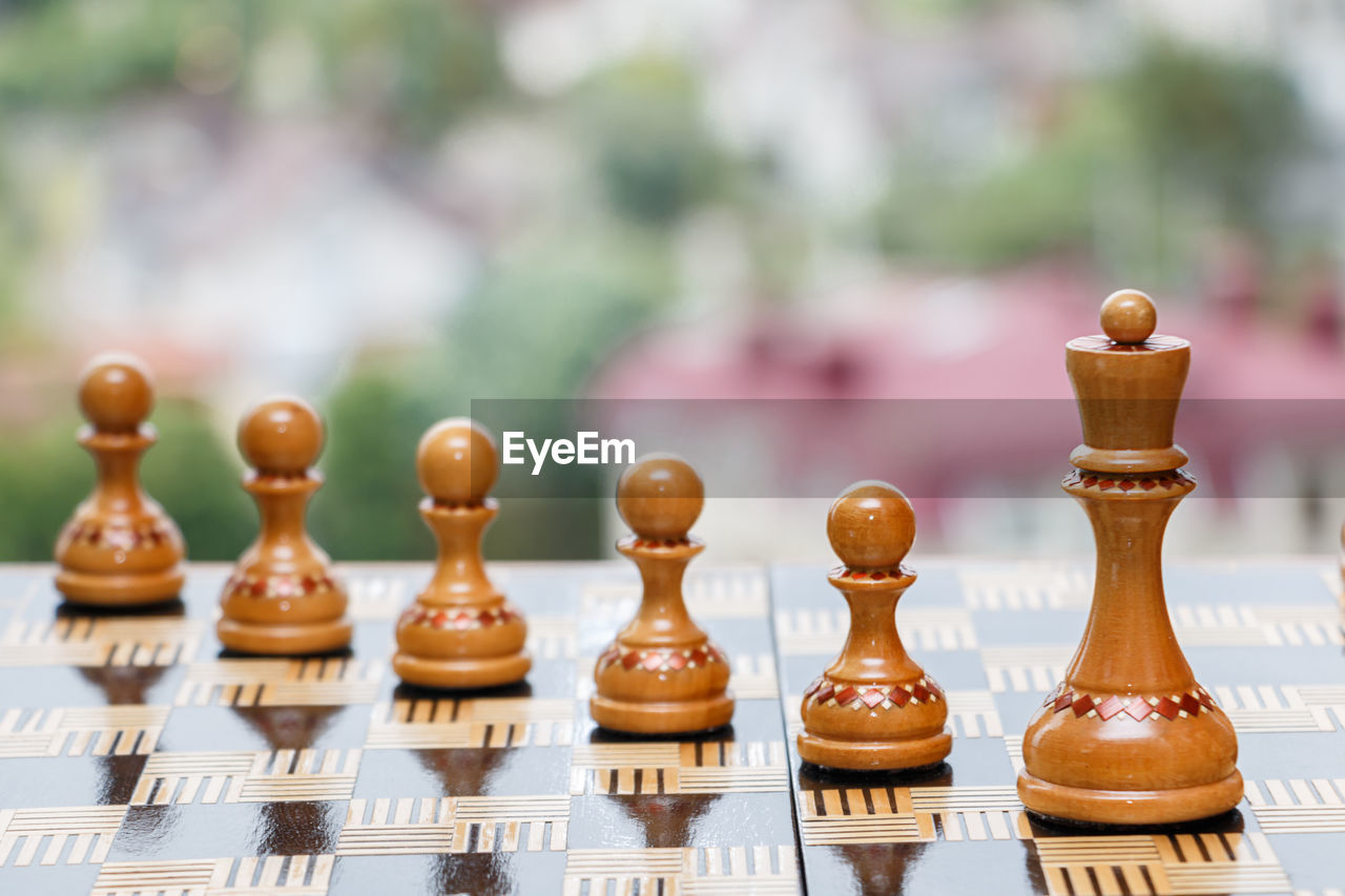 CLOSE-UP OF CHESS PIECES ON TABLE AGAINST BLURRED BACKGROUND