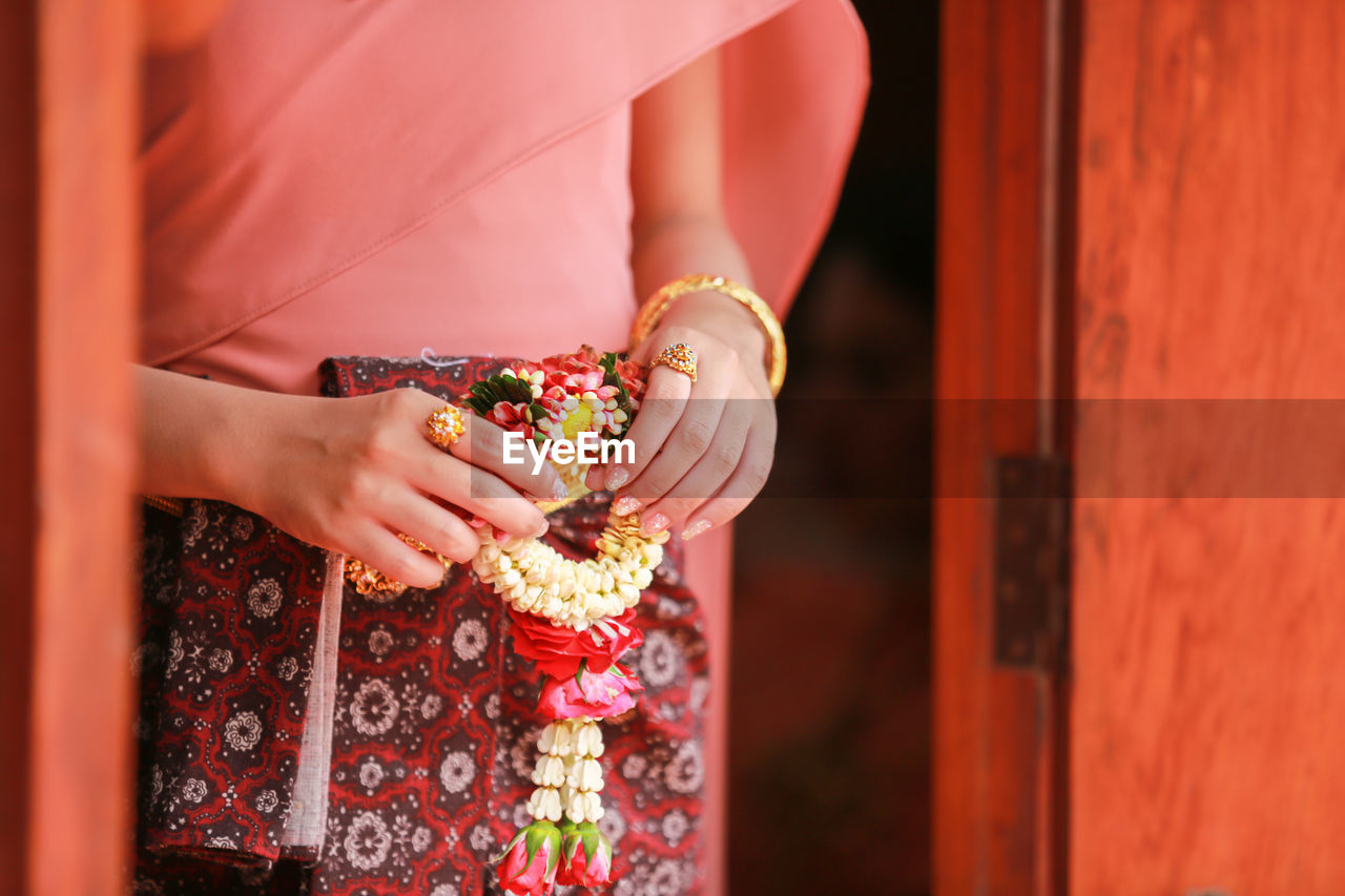 Midsection of woman holding flower garland