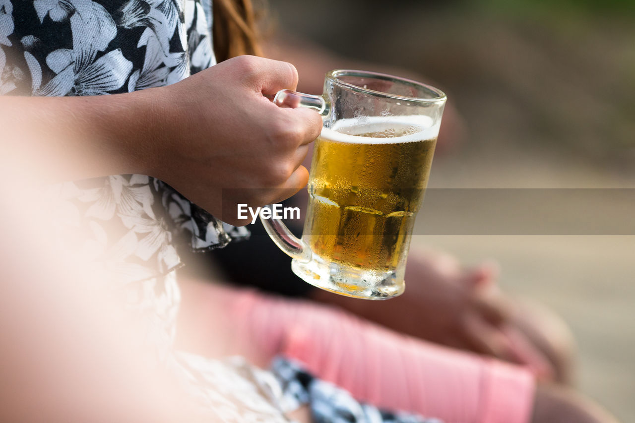 MIDSECTION OF MAN DRINKING BEER GLASS