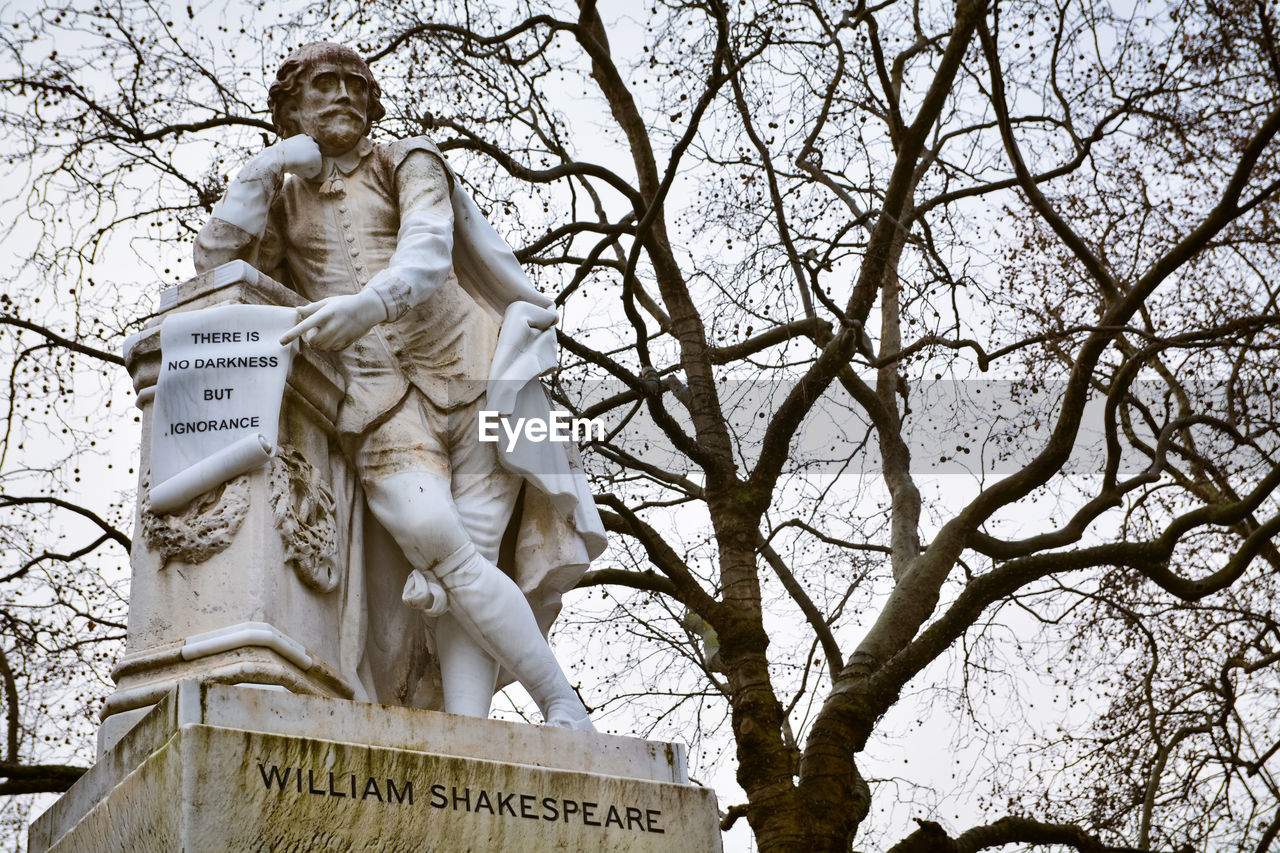 Low angle view of statues against bare trees