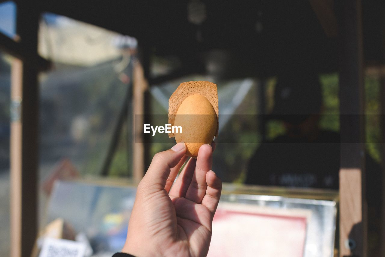 Close-up of hand holding egg shaped pastry