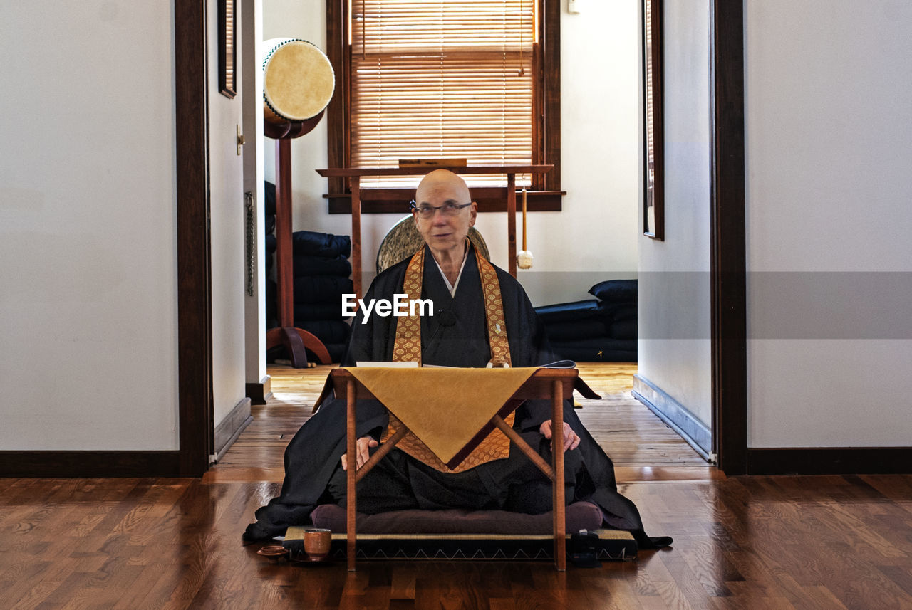 YOUNG WOMAN SITTING ON TABLE WITH CHAIR AT HOME