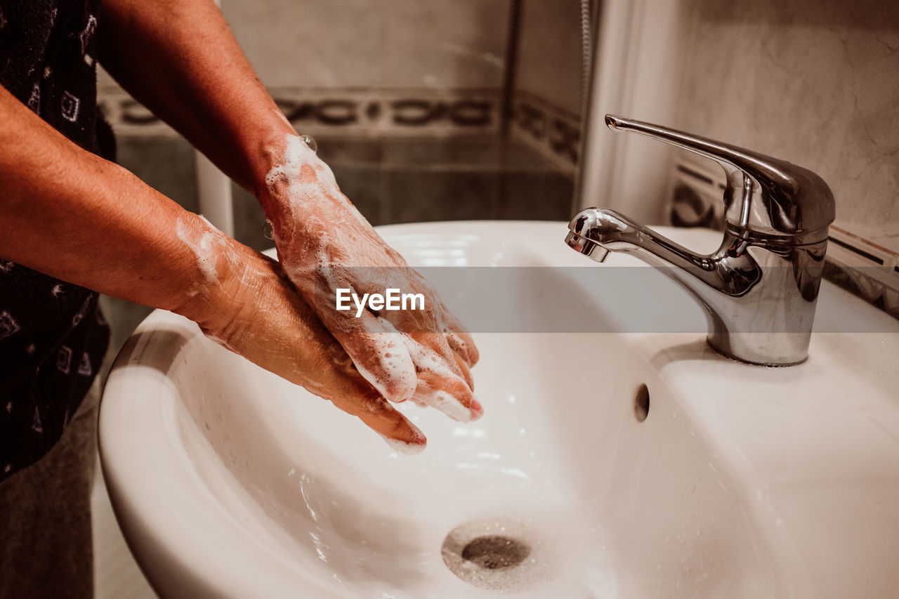 Midsection of man washing hands in sink
