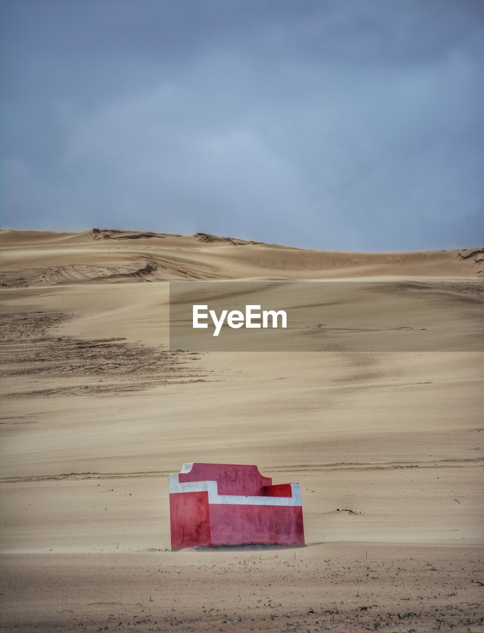 Red sofa on idyllic desert against sky