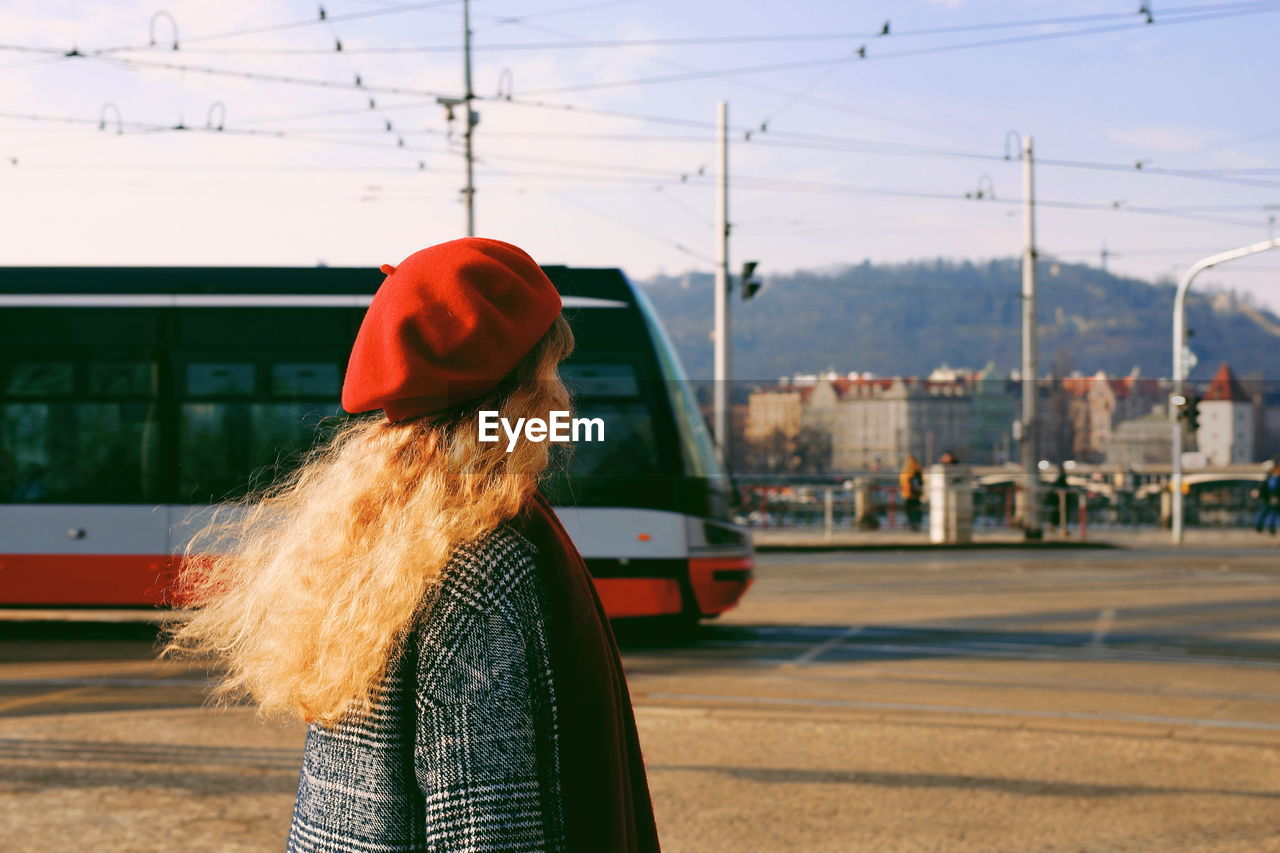 Woman wearing red hat while standing on street in city