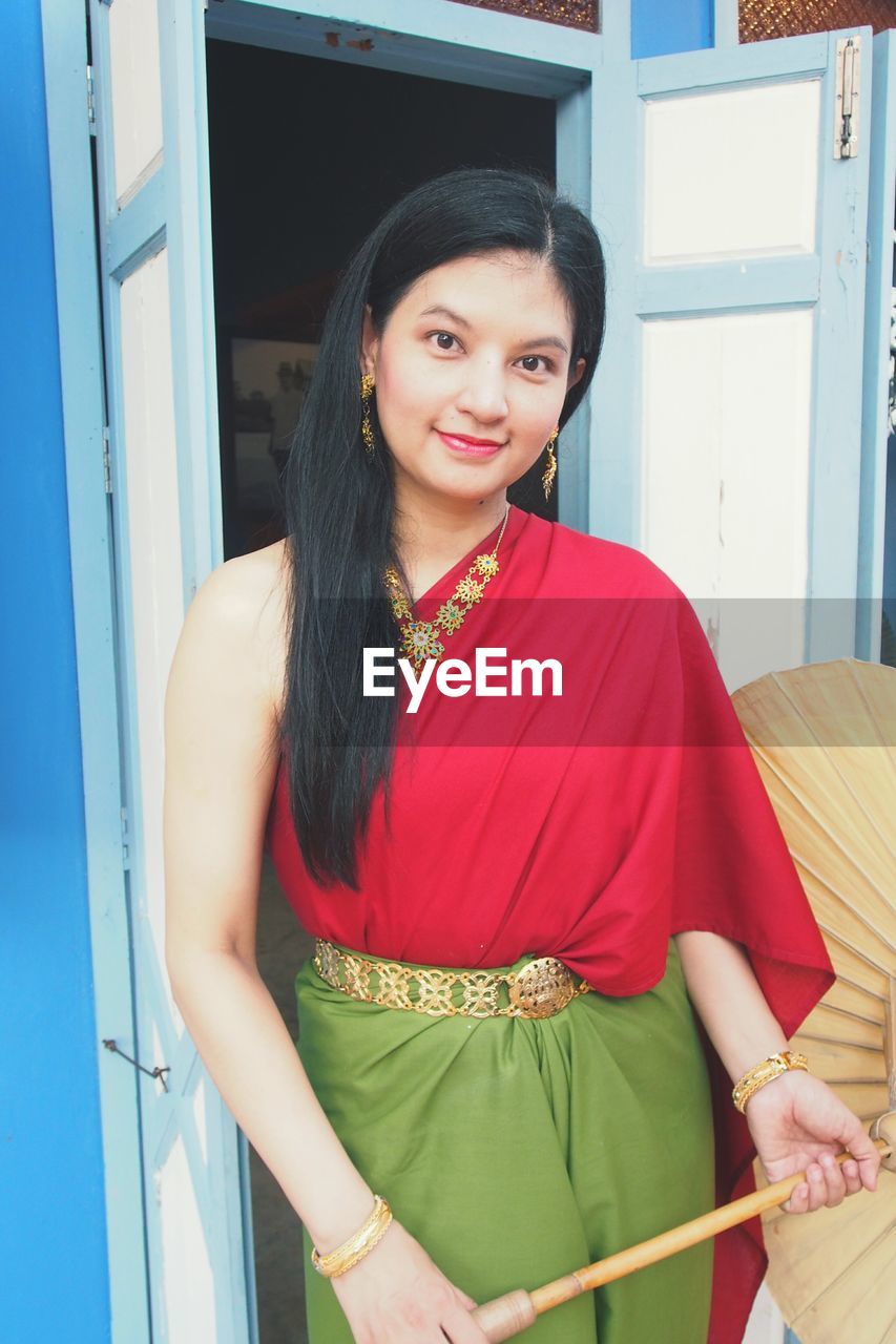 Portrait of woman wearing traditional clothing while standing against door