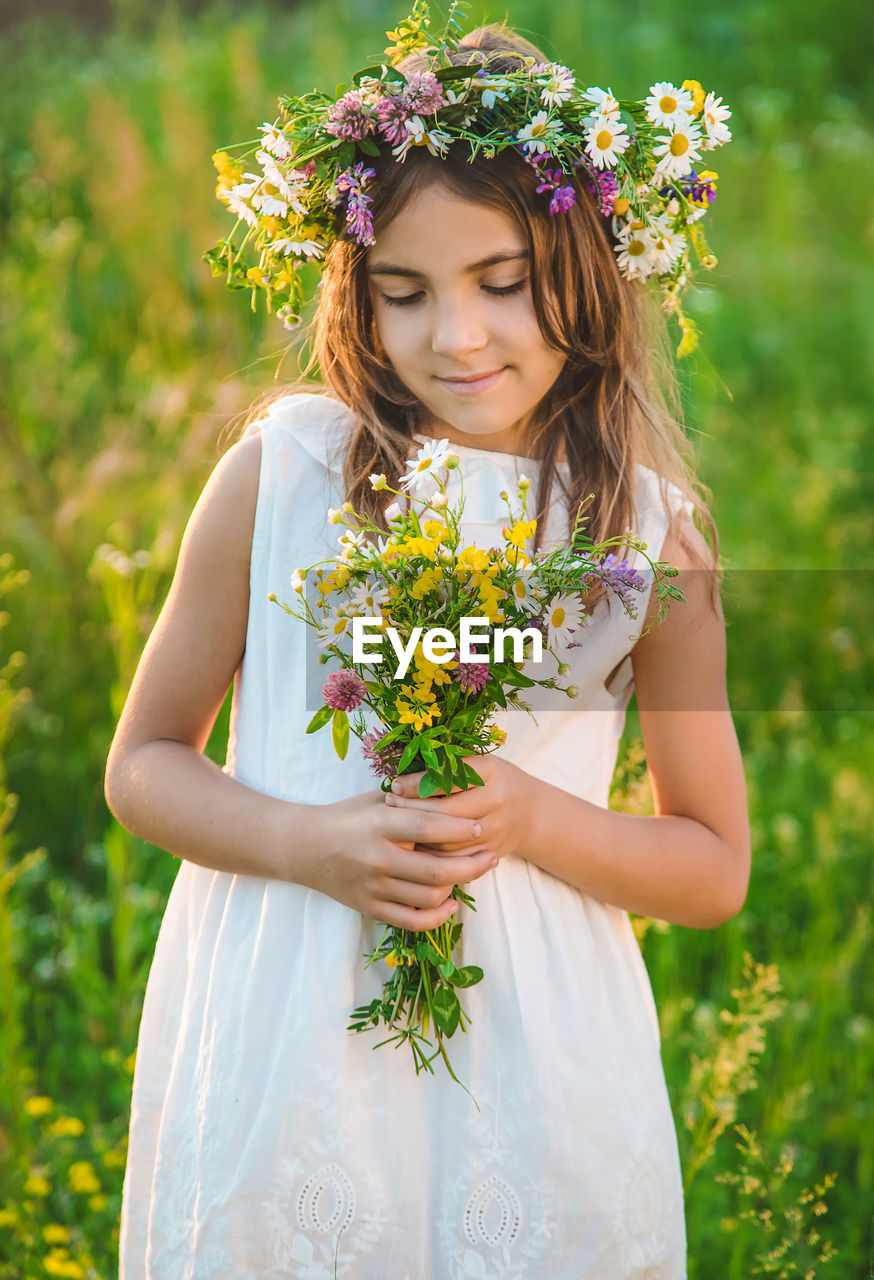 Girl wearing floral crown holding flowers