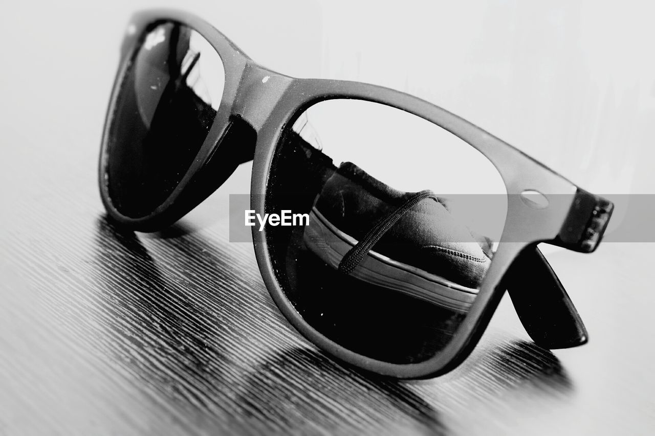 CLOSE-UP OF SUNGLASSES ON TABLE WITH REFLECTION