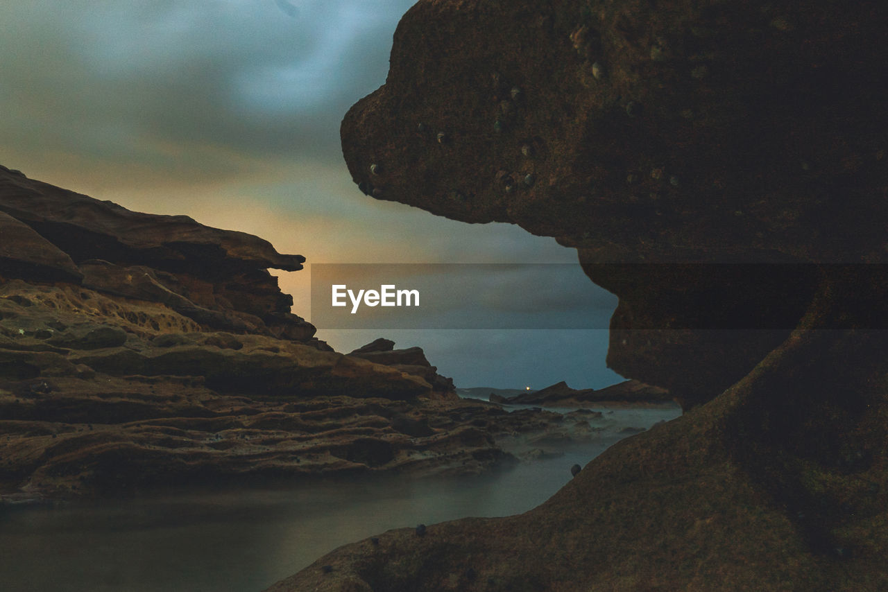 ROCK FORMATION ON SEA AGAINST SKY