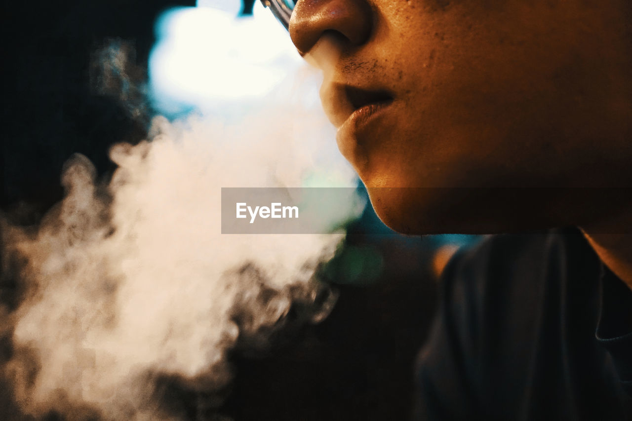 Close-up of man emitting smoke