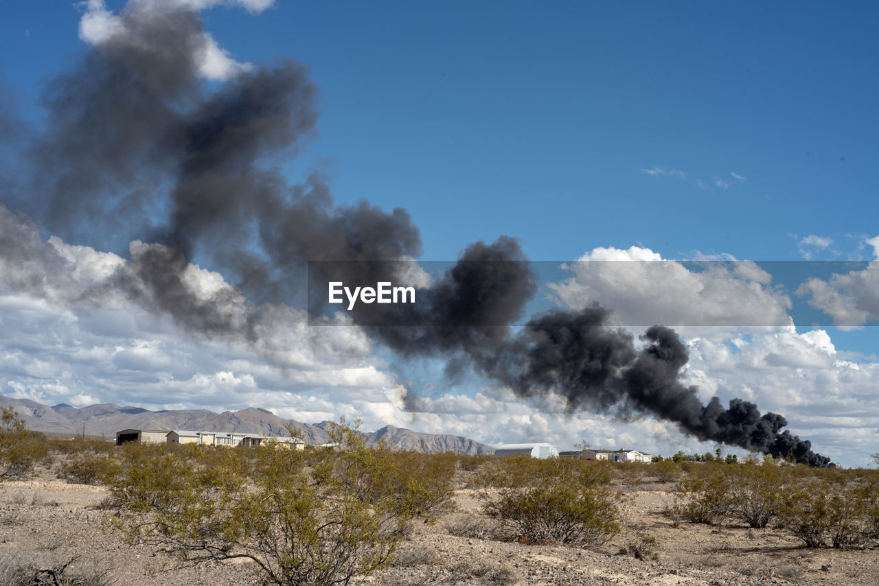 Smoke over landscape against sky