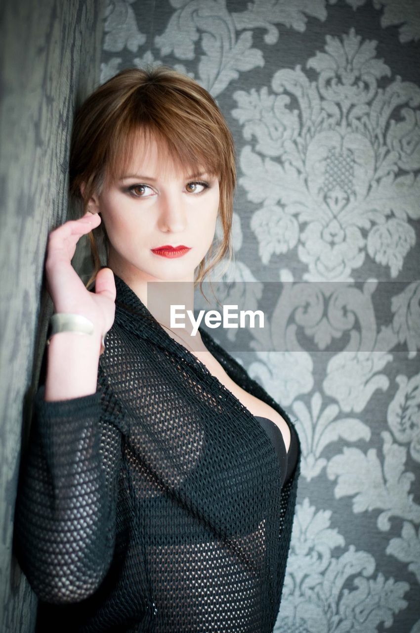PORTRAIT OF BEAUTIFUL WOMAN STANDING IN BEDROOM