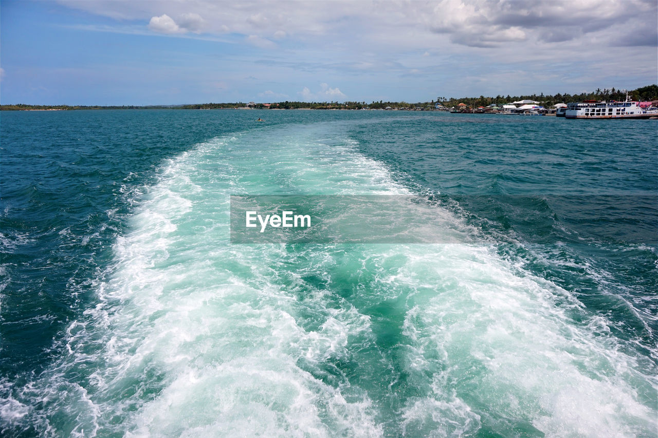 Wake at sea against sky