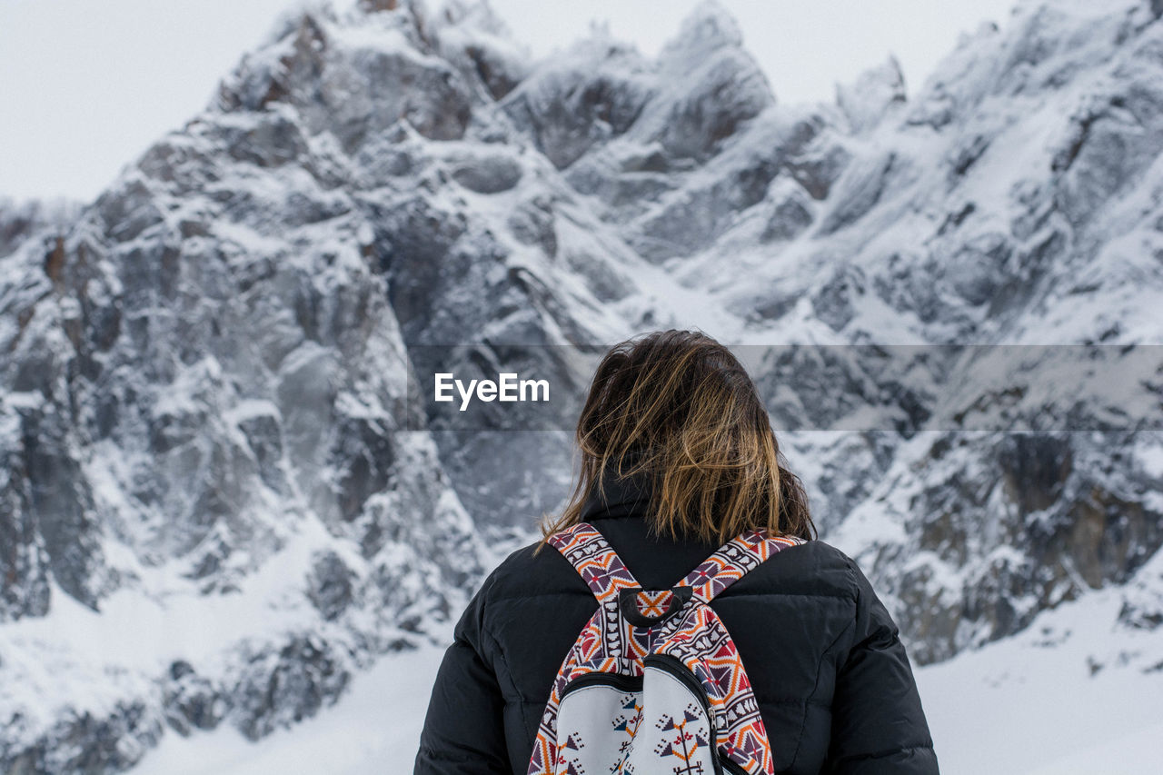 Low angle view of woman standing against snowcapped mountains