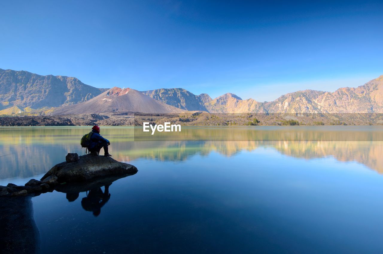 Reflection of man in lake against sky