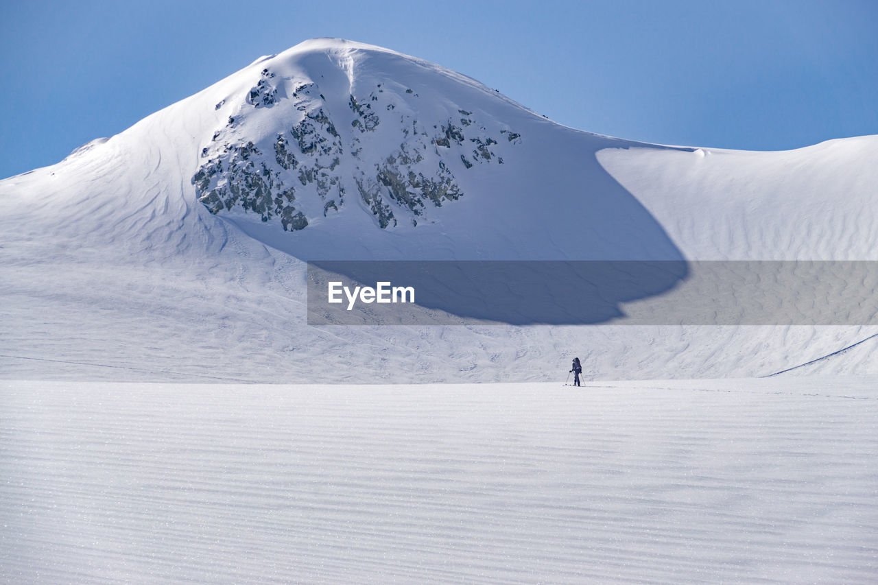 Man skiing on snow covered field against sky
