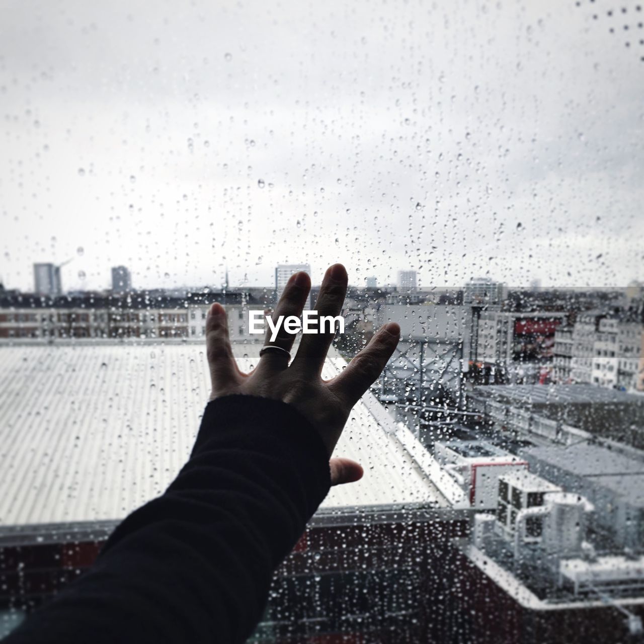 Hand touching wet glass window