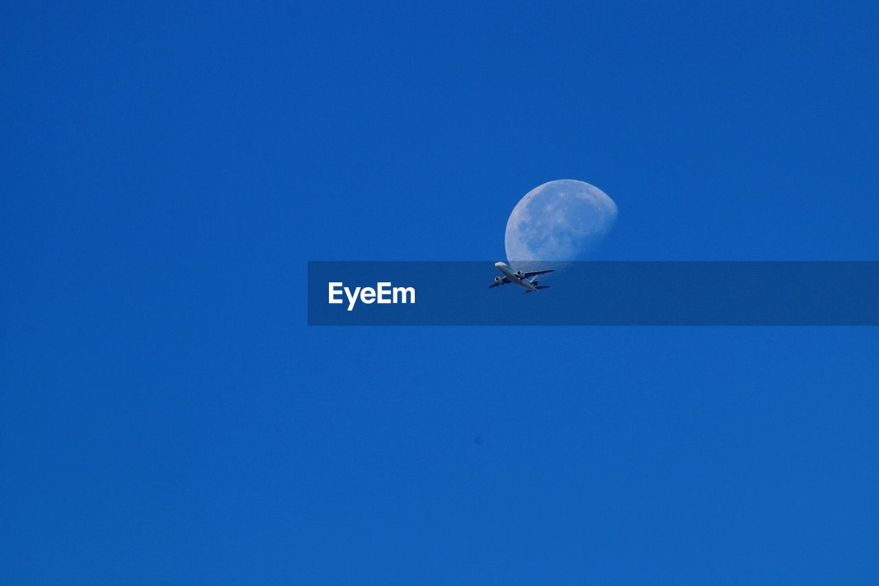 Low angle view of airplane against clear blue sky