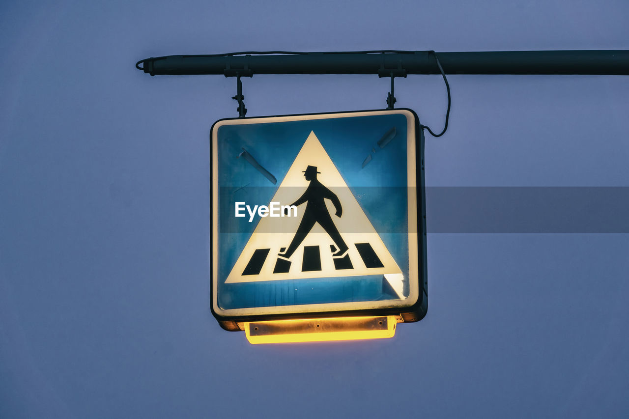 Low angle view of road sign against clear blue sky