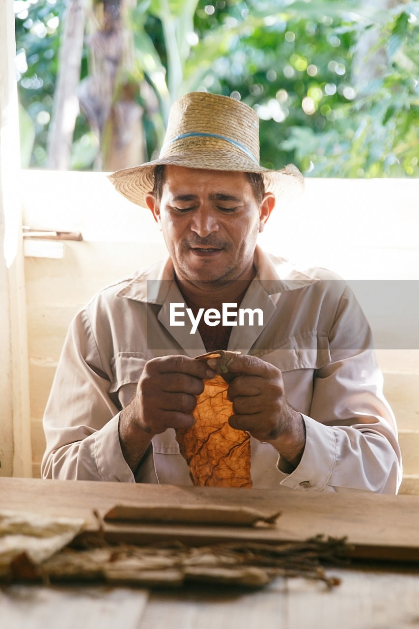 Man wearing hat holding leaf