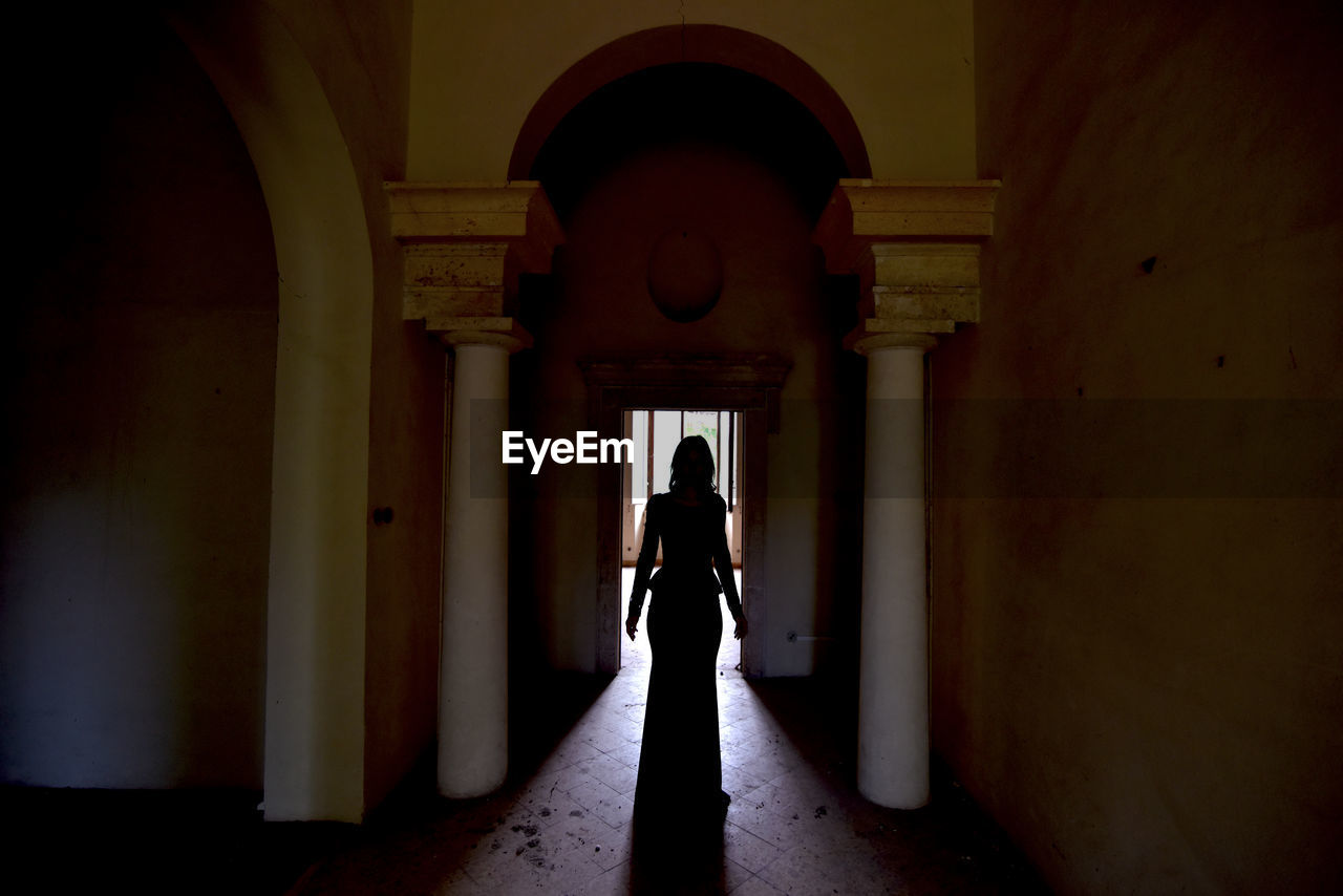 Rear view of woman standing in corridor of building