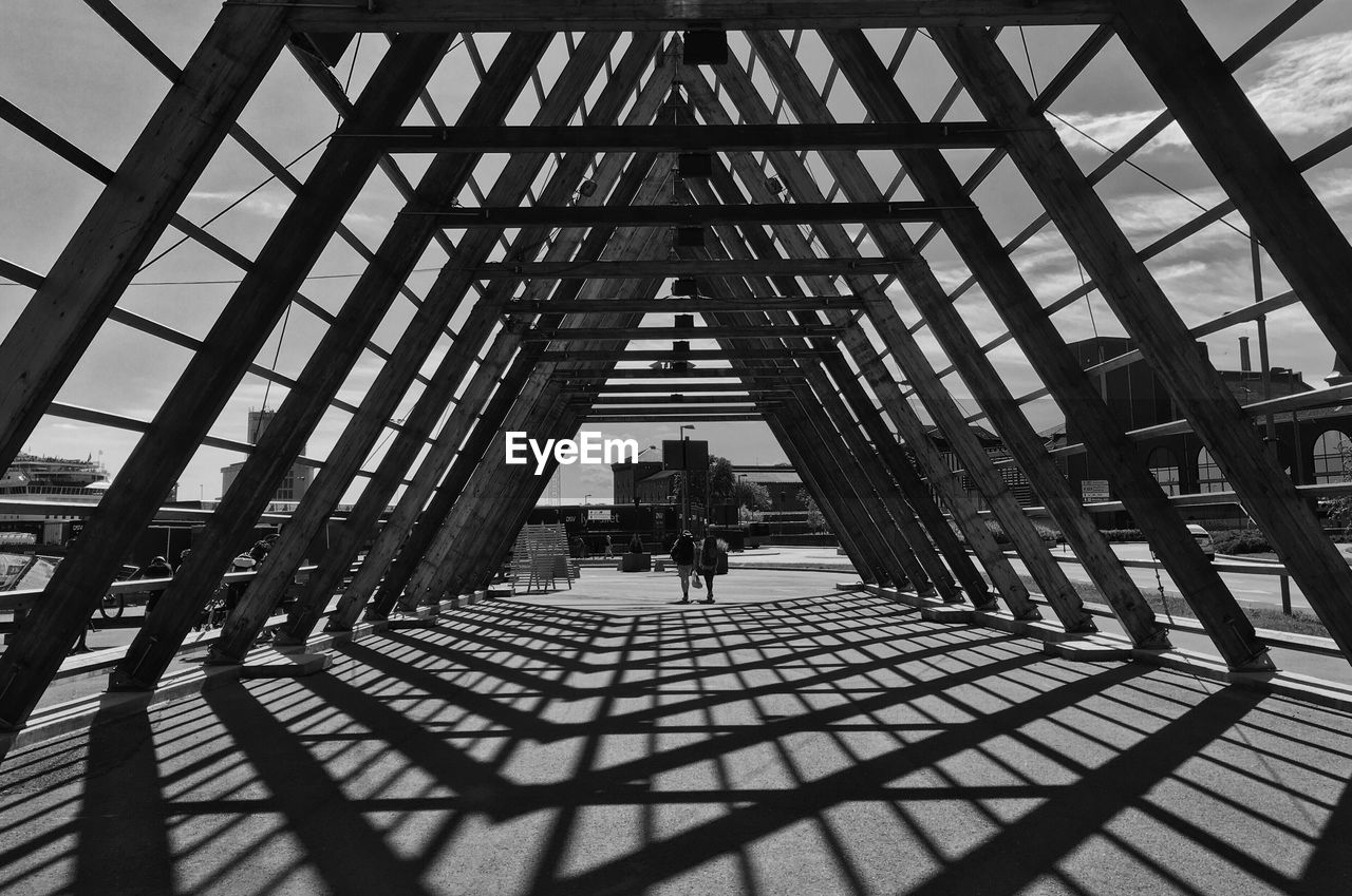 Shadow of metallic built structure falling on footpath in city