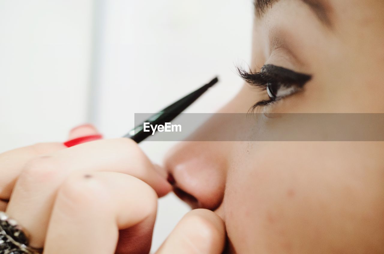 Cropped image of woman applying eyeliner