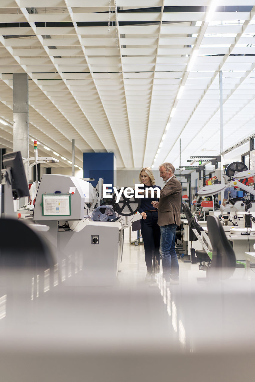 Businesswoman with colleague operating machinery in industry