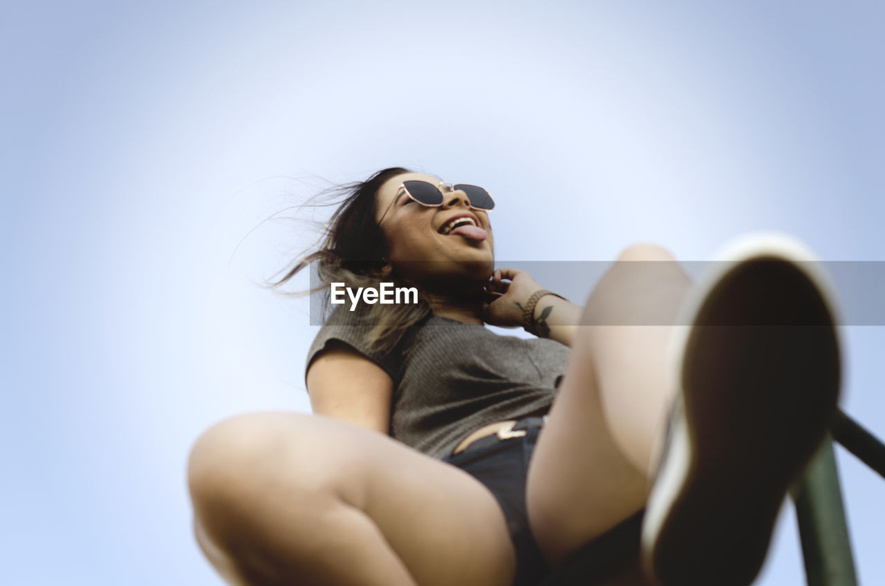 LOW ANGLE VIEW OF WOMAN SITTING OUTDOORS