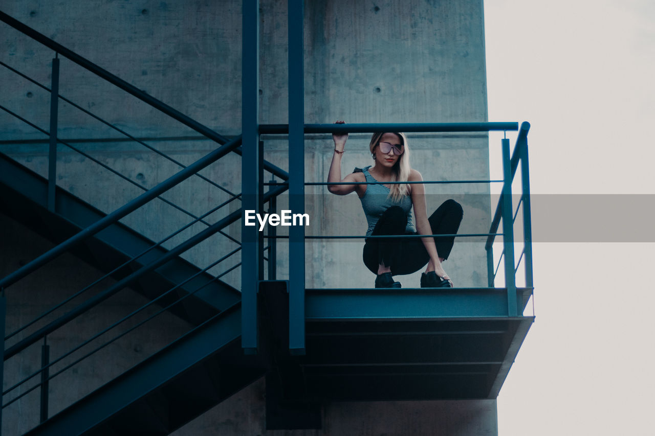Low angle view of woman crouching on staircase