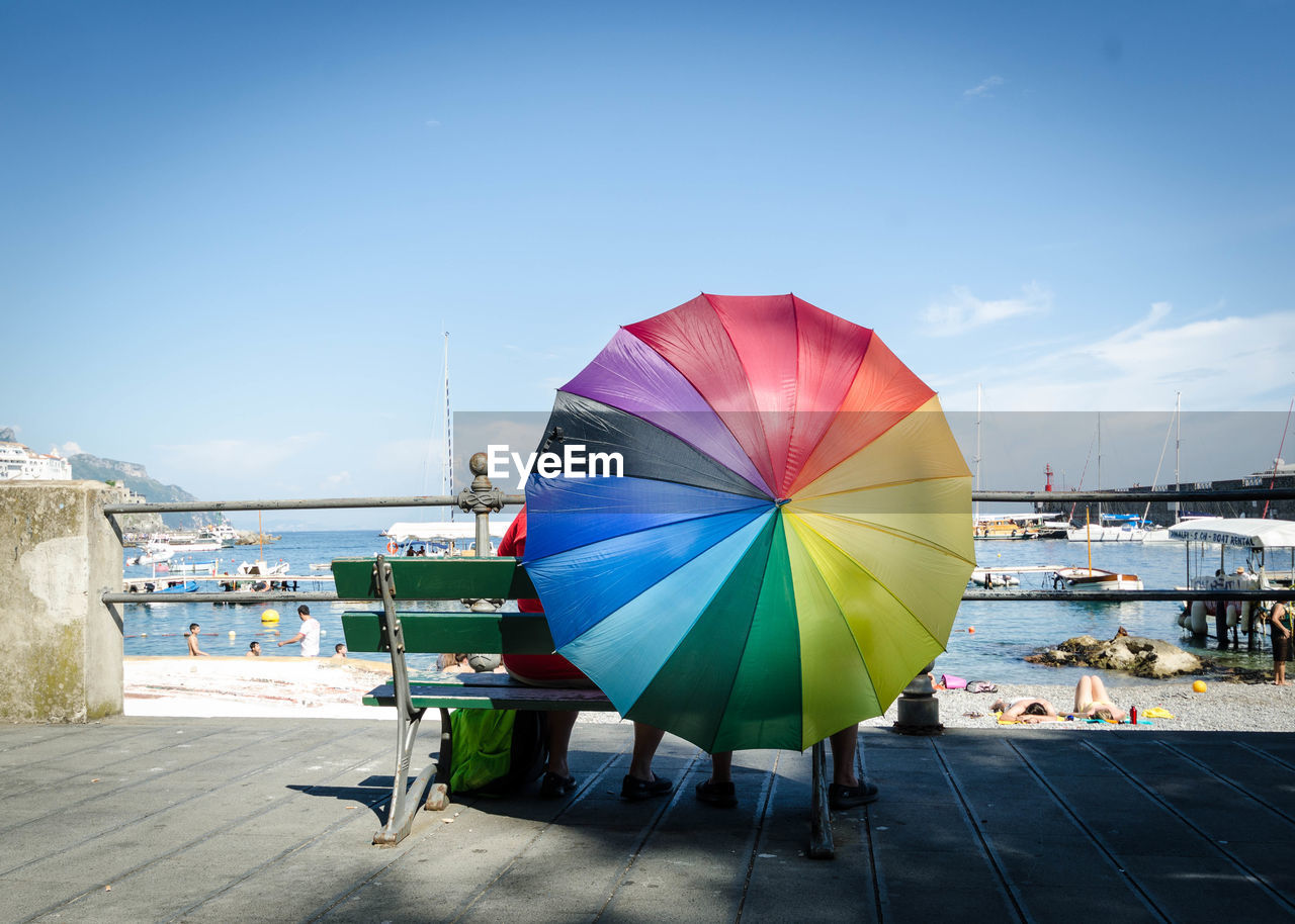 Multi colored umbrella by sea against sky