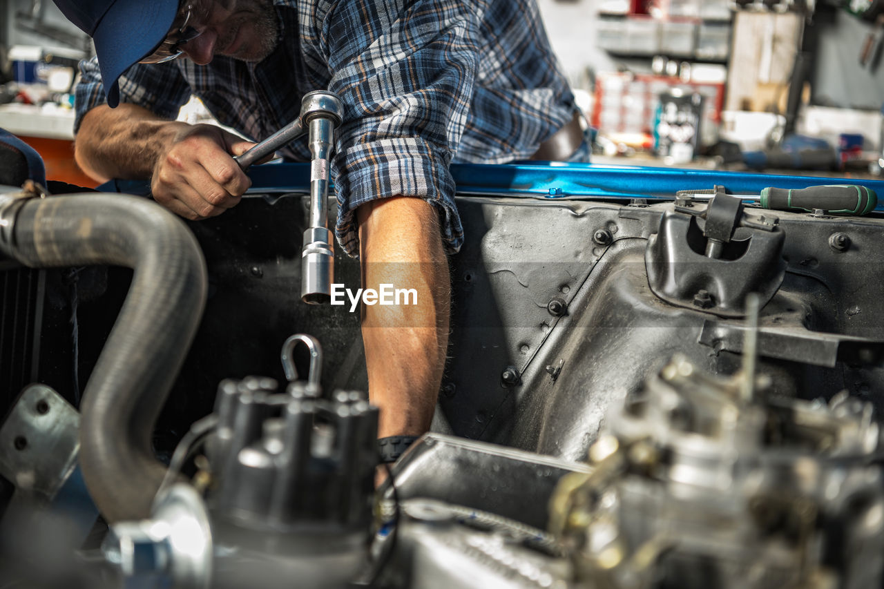 midsection of man repairing car engine