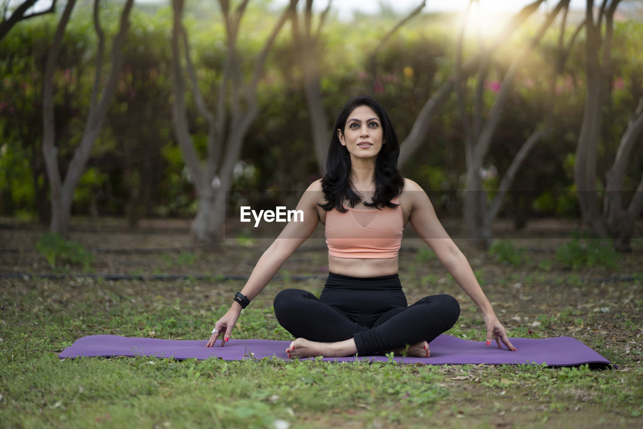 Full length of woman meditating while sitting outdoors